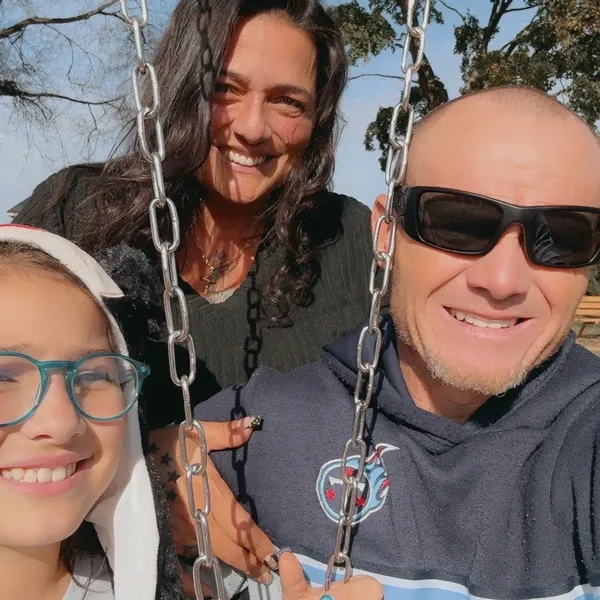 Danielle with family members sitting on swings outdoors in a close-up photo.